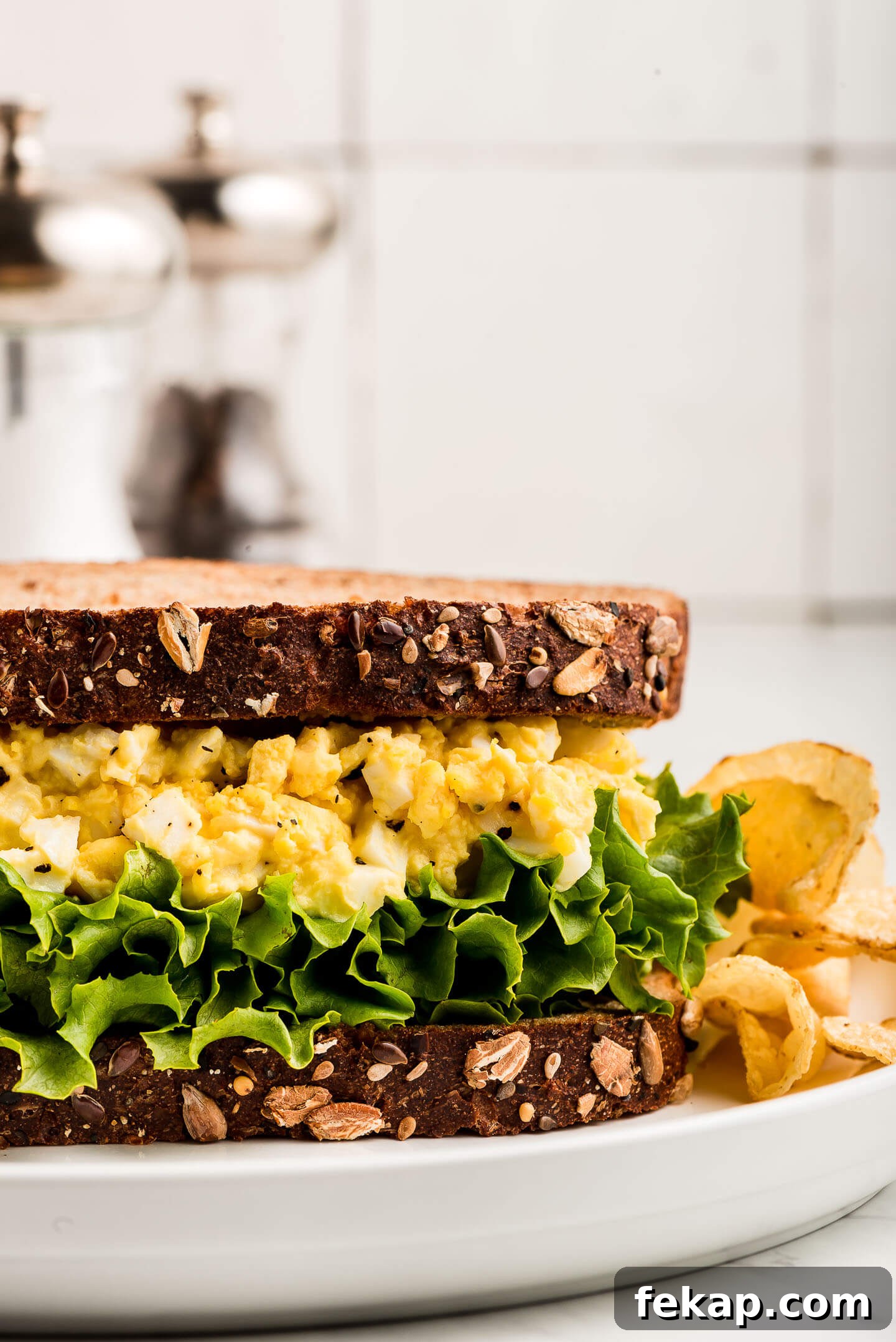 Close up side view of an Egg Salad Sandwich with chips at the side.