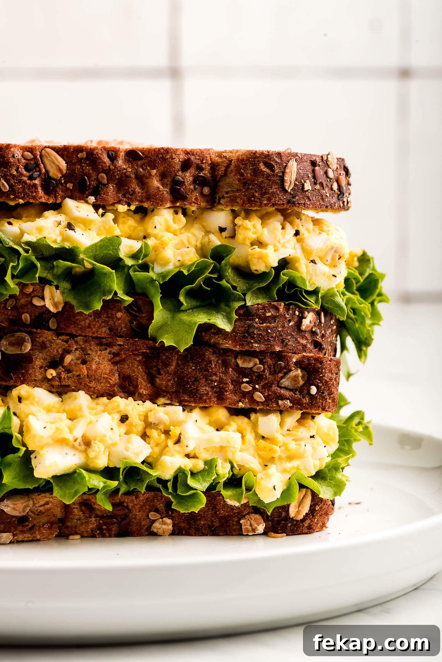 Close up of two Egg Salad Sandwiches stacked on top of each other on a plate.