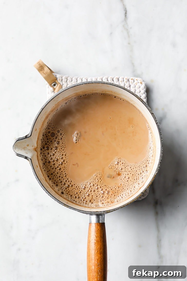 Authentic Masala Chai Recipe: Aromatic Spiced Tea 4 Finished Masala chai on a marbled surface in a white saucepan