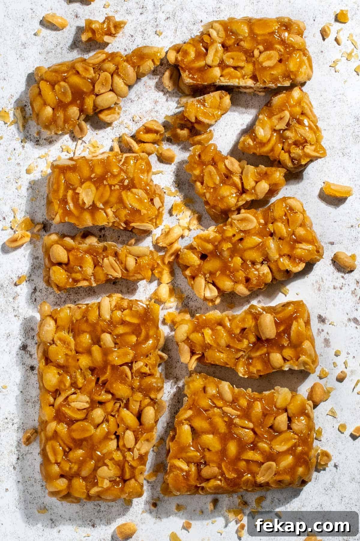 Peanut Brittle Without Corn Syrup 2 Peanut brittle without corn syrup broken into pieces on a white background.