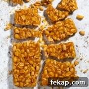 Peanut Brittle Without Corn Syrup 11 Peanut brittle without corn syrup broken into pieces on a white background.