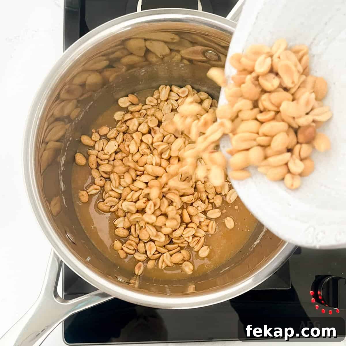 Peanut Brittle Without Corn Syrup 8 Adding peanuts to the caramel in a pan.