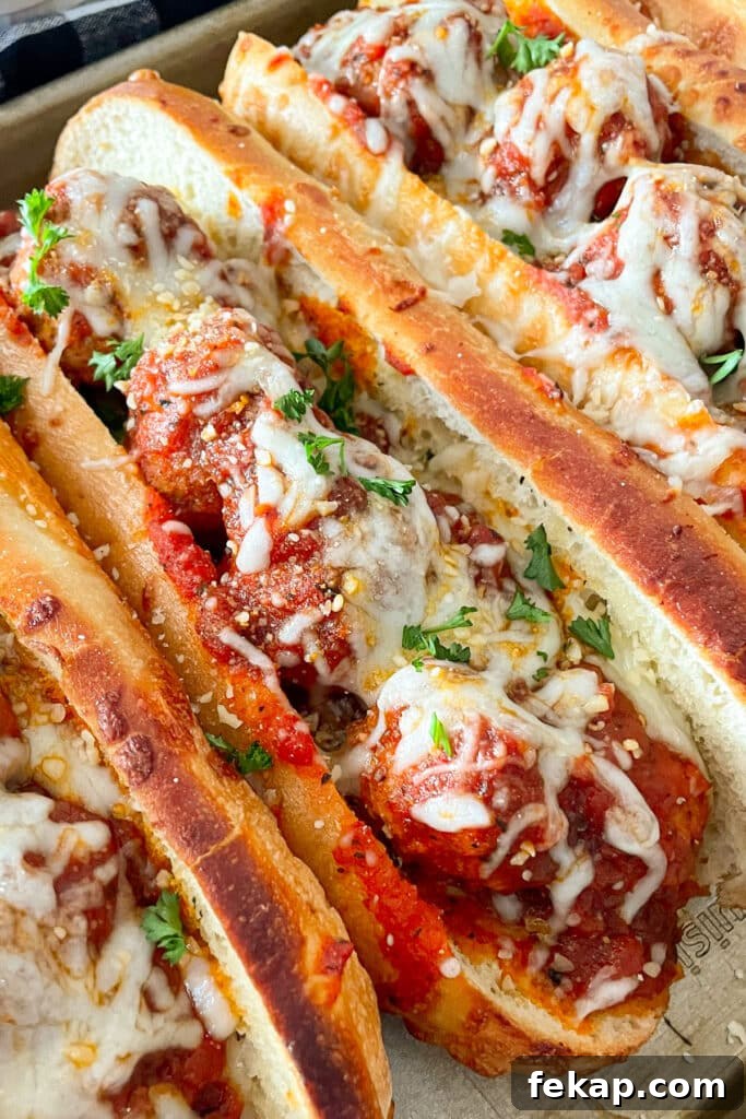 Slow Cooker Italian Meatball Subs Recipe 2 close up shot of meatball sub topped with mozzarella cheese and parsley
