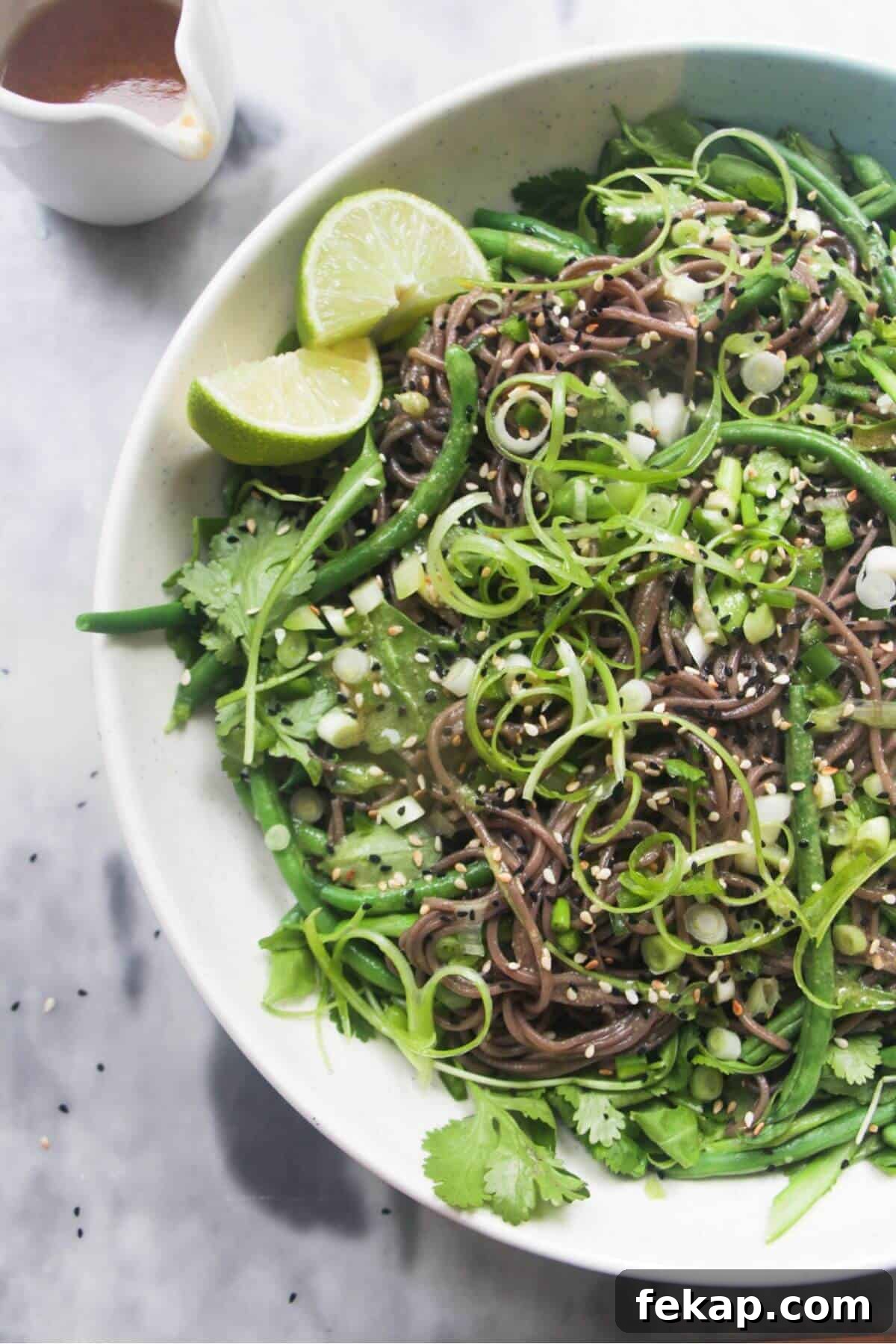 Green Goddess Soba Noodle Salad with Creamy Avocado Dressing 2 Cold Asian soba noodle salad with lots of green vegetables in a large serving platter, with jug of dressing on the side.