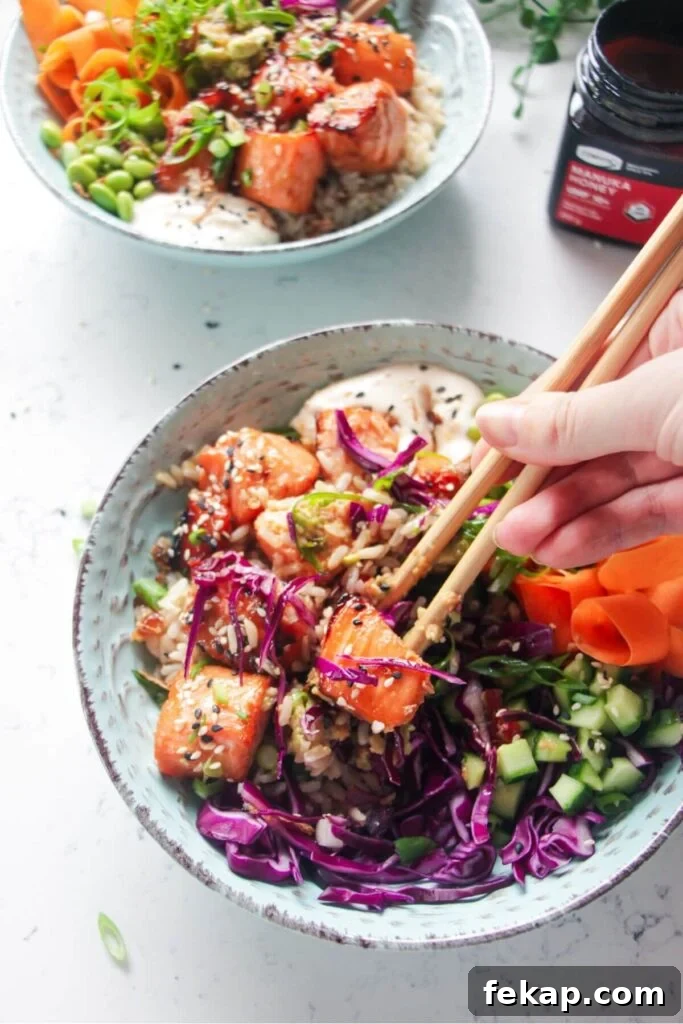 Green Goddess Soba Noodle Salad with Creamy Avocado Dressing 11 Hands holding chopsticks, picking up piece of salmon from poke bowl.