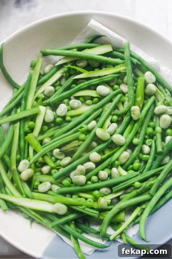 Green Goddess Soba Noodle Salad with Creamy Avocado Dressing 5 Green beans, asparagus, edamame beans and peas draining in a large serving bowl.