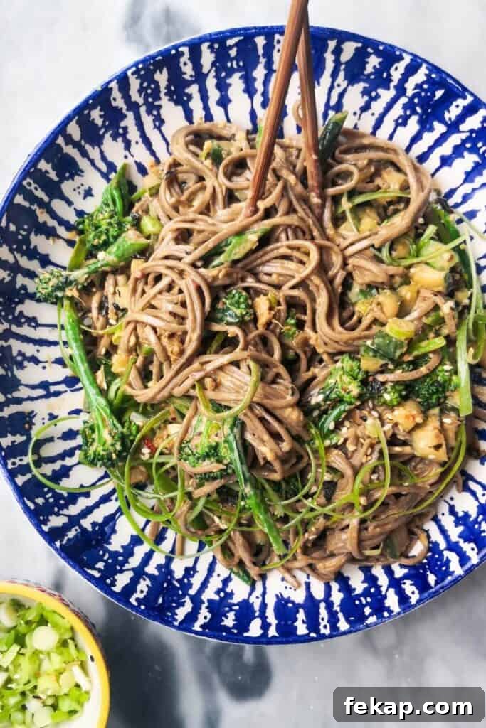 Green Goddess Soba Noodle Salad with Creamy Avocado Dressing 10 Sesame soba noodles with cucumber and broccolini in a white and blue bowl with chopsticks.