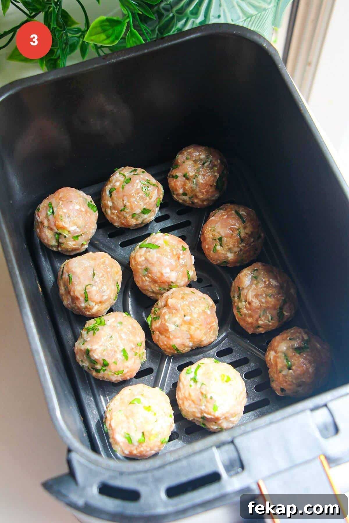 Rolled dumpling meatballs in air fryer basket.