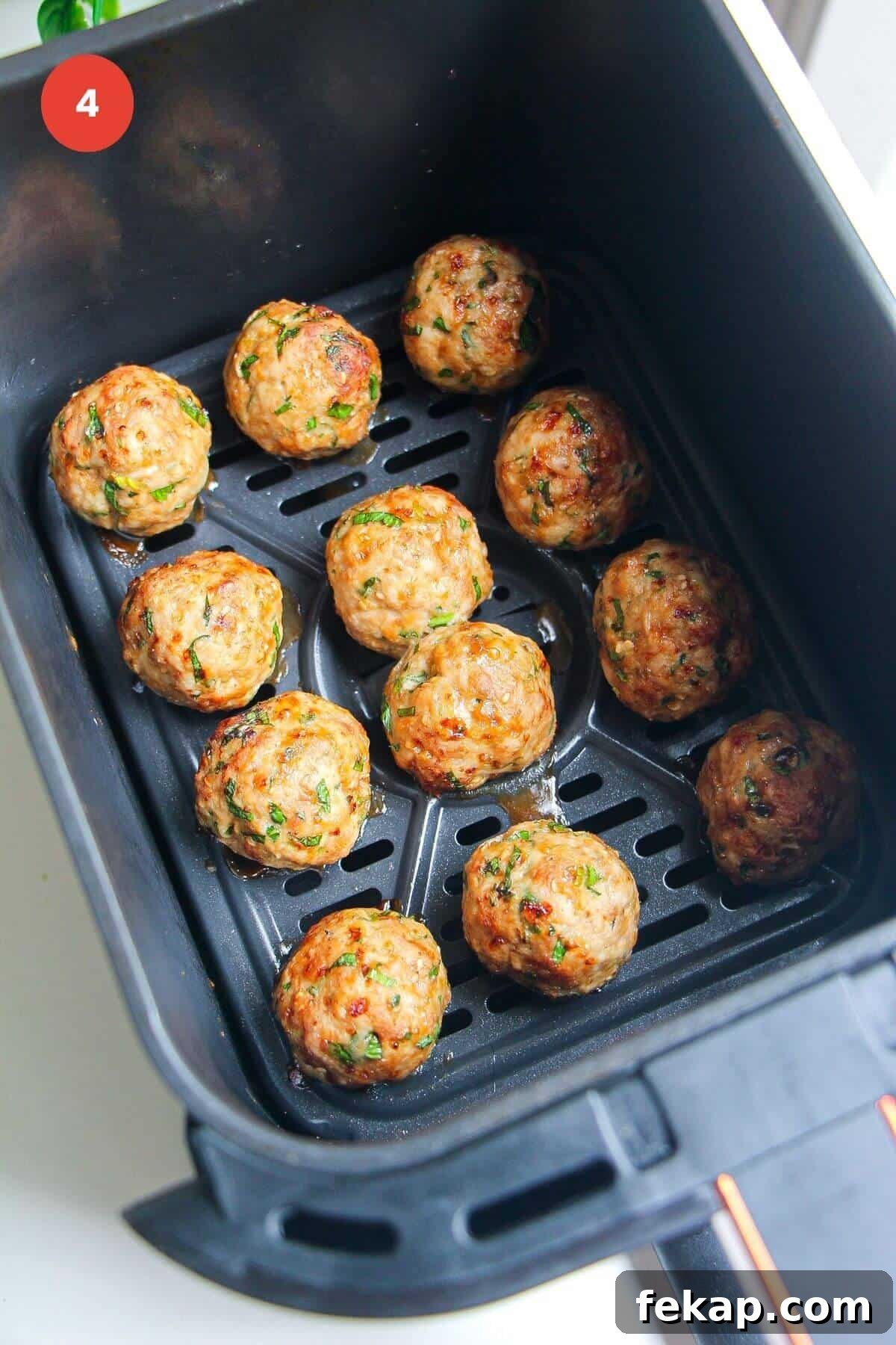 Cooked dumpling meatballs in air fryer basket.