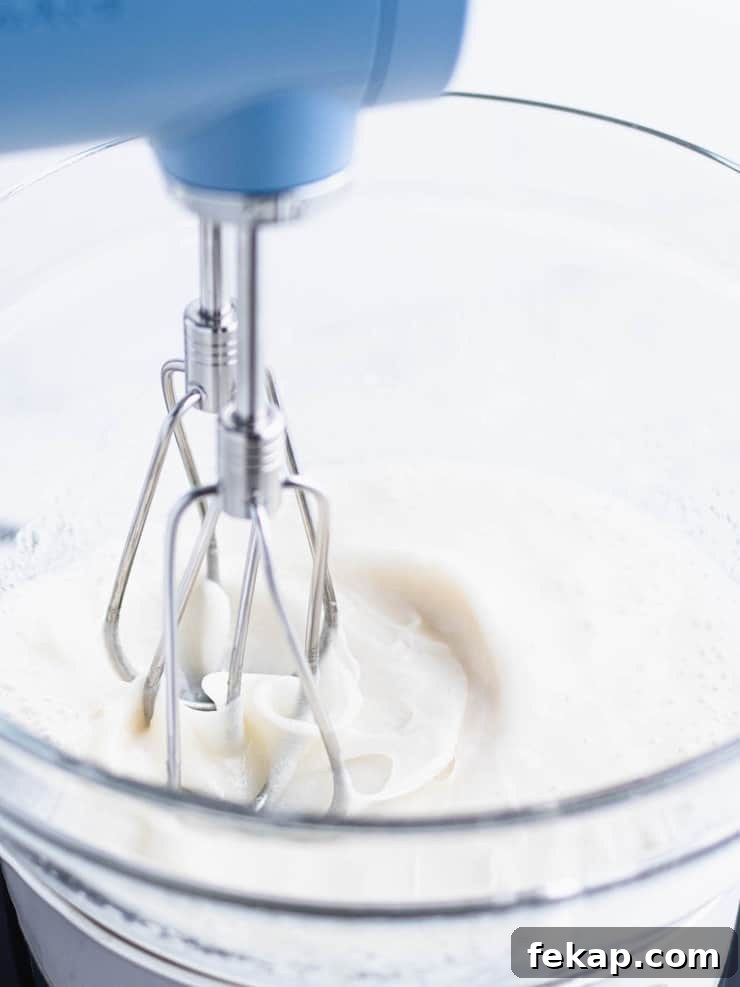 Close up of frosting being whipped in a bowl over a pot of simmering water.