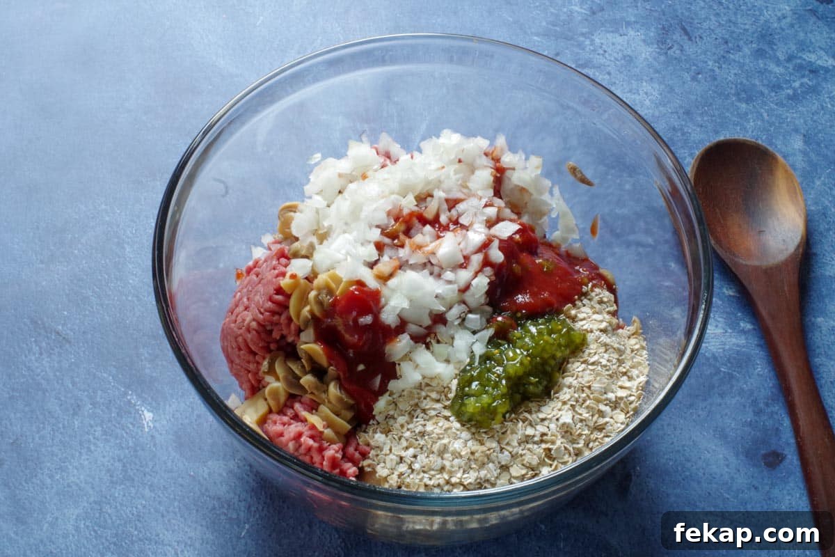 Old-Fashioned Gluten-Free, Dairy-Free Meatloaf (No Eggs or Milk) 5 meatloaf ingredients in a large glass mixing bowl, with a wooden spoon on the side