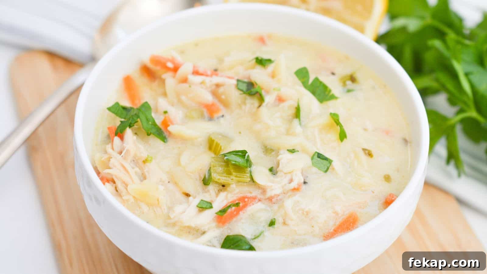 15 Soups and Stews That Make You Forget It's Summer 16 Lemon chicken soup in a white bowl with lemon slices.