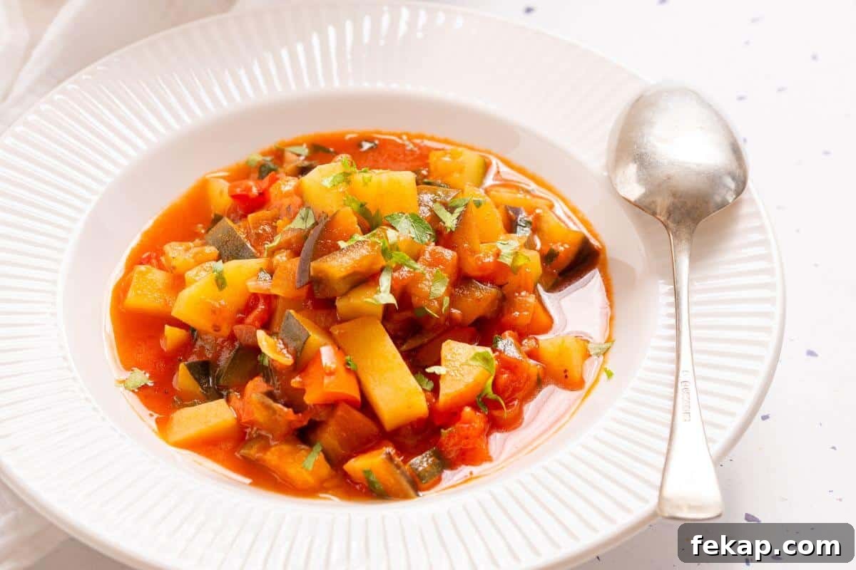 15 Soups and Stews That Make You Forget It's Summer 10 A pot of Italian vegetable stew with a spoon, garnished with chopped green herbs, on a white tablecloth with a small bowl of parsley on the side.