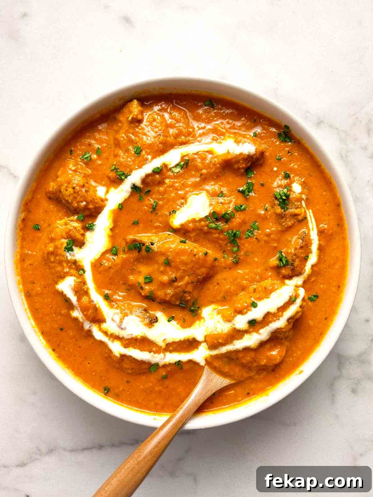 Creamy Butter Chicken Recipe: Authentic Indian Flavor 2 bowl of butter chicken with parsley and cream garnished on top.