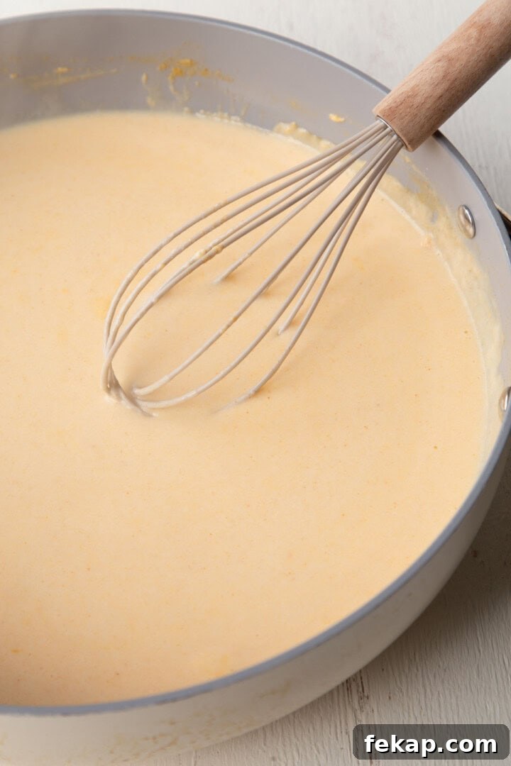 Creamy Old Fashioned Mac and Cheese Recipe 7 creamy, milky sauce in a skillet with a whisk.