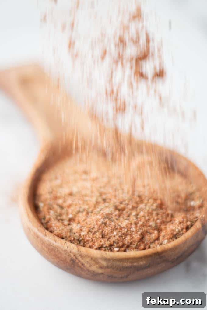 Cajun seasoning mix being sprinkled into a wooden spoon.