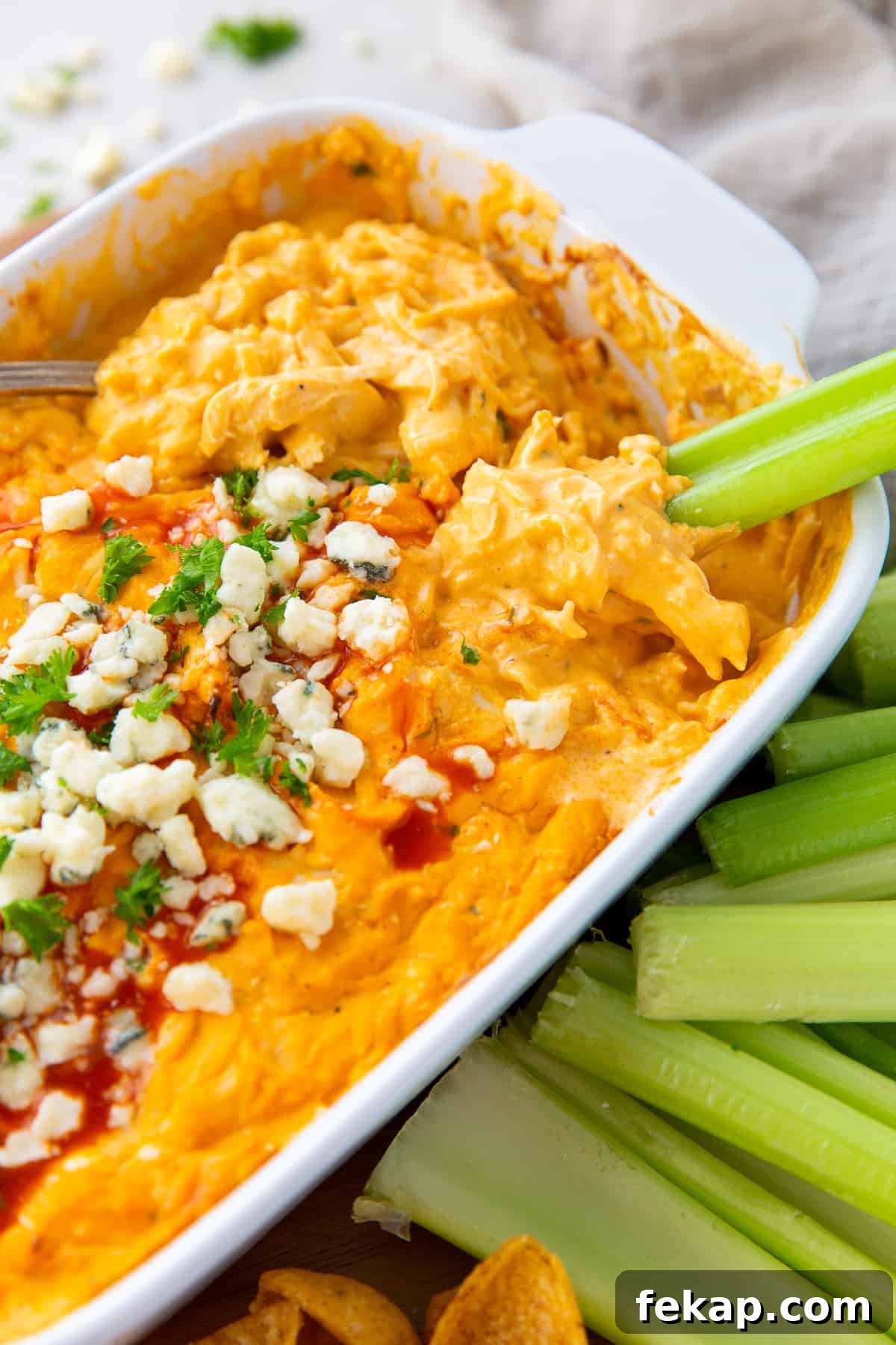 A celery stick dipping into Buffalo Chicken Dip.