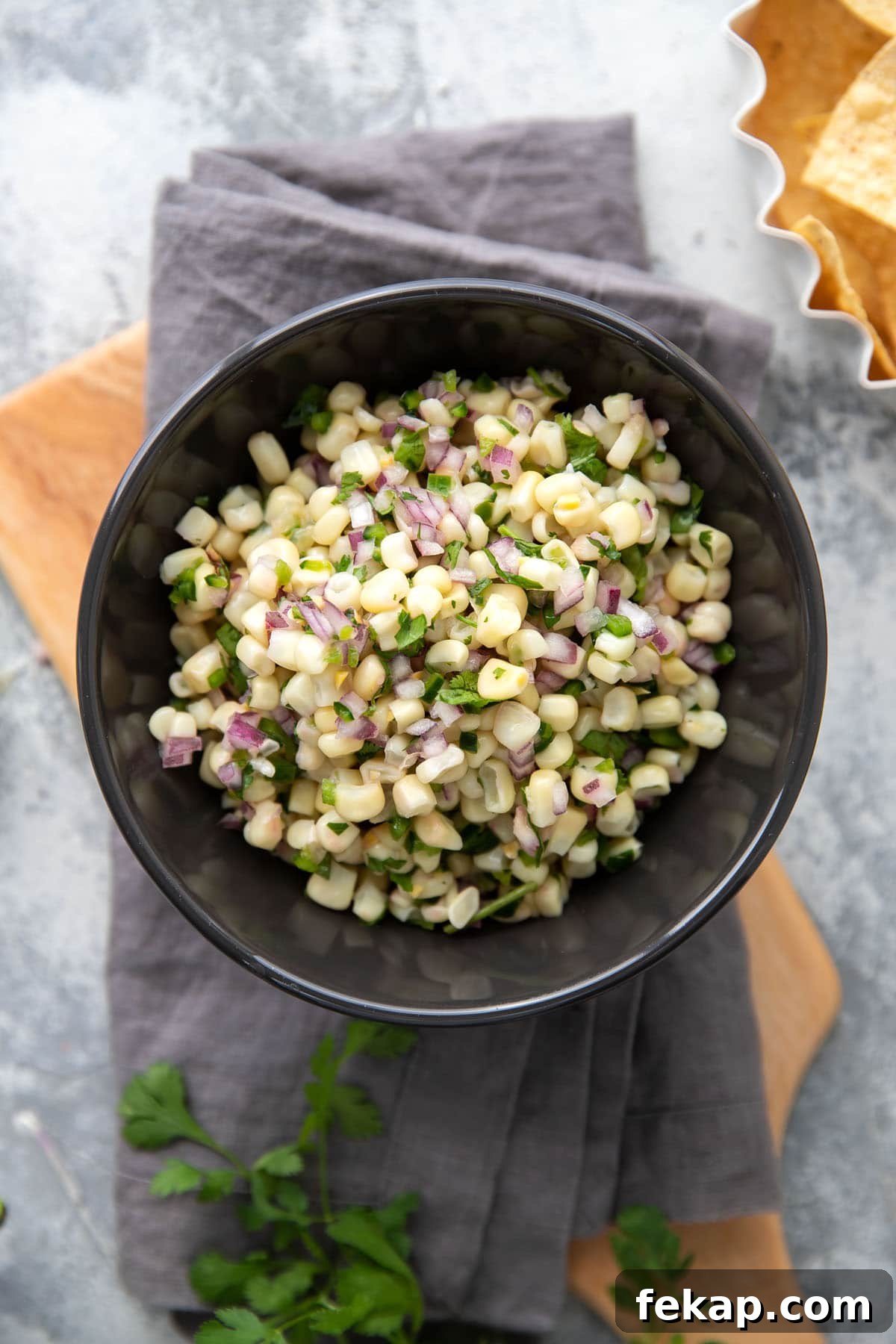 white corn salsa with red onions and peppers in a grey bowl