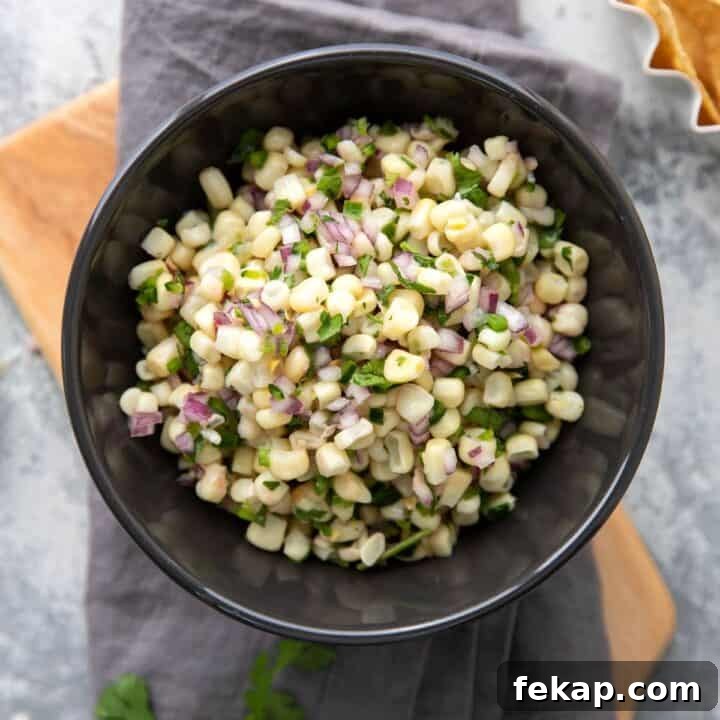 white corn salsa with red onions and peppers in a grey bowl