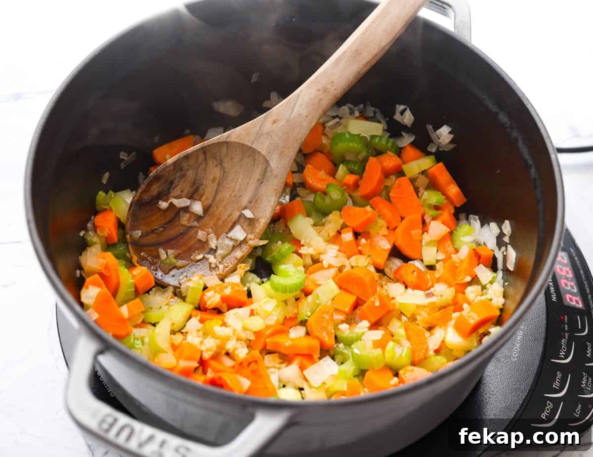 Carrots, onion, and celery cooking in a pot.