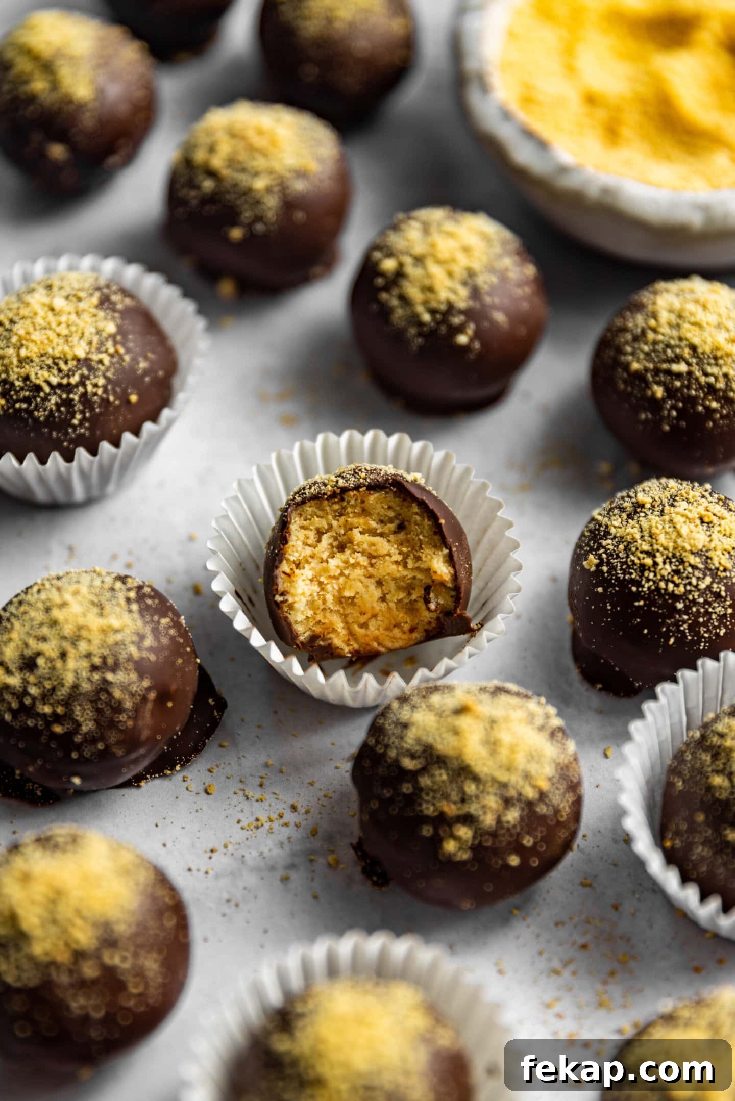 No-bake cheesecake ball with a bite missing surrounded by other chocolate covered cheesecake balls.