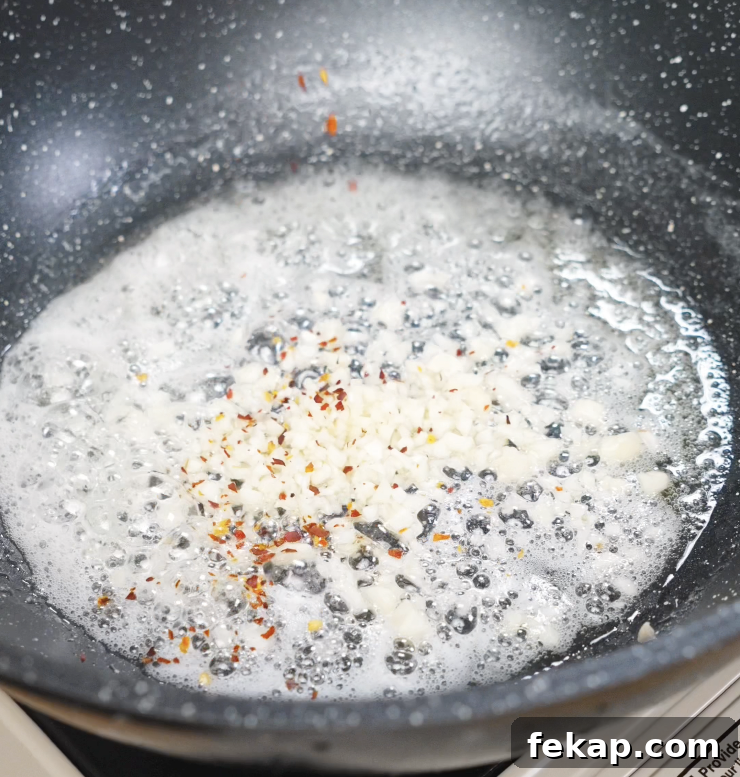 Spicy Chili Garlic Butter Noodles Recipe 5 Minced garlic sizzling in melted butter with red chili flakes, releasing a fragrant aroma.
