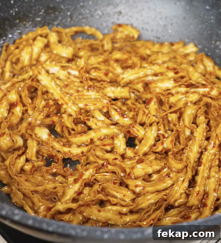 Spicy Chili Garlic Butter Noodles Recipe 7 Cooked noodles being tossed into the pan, coated in the glossy, spicy chili garlic butter sauce.