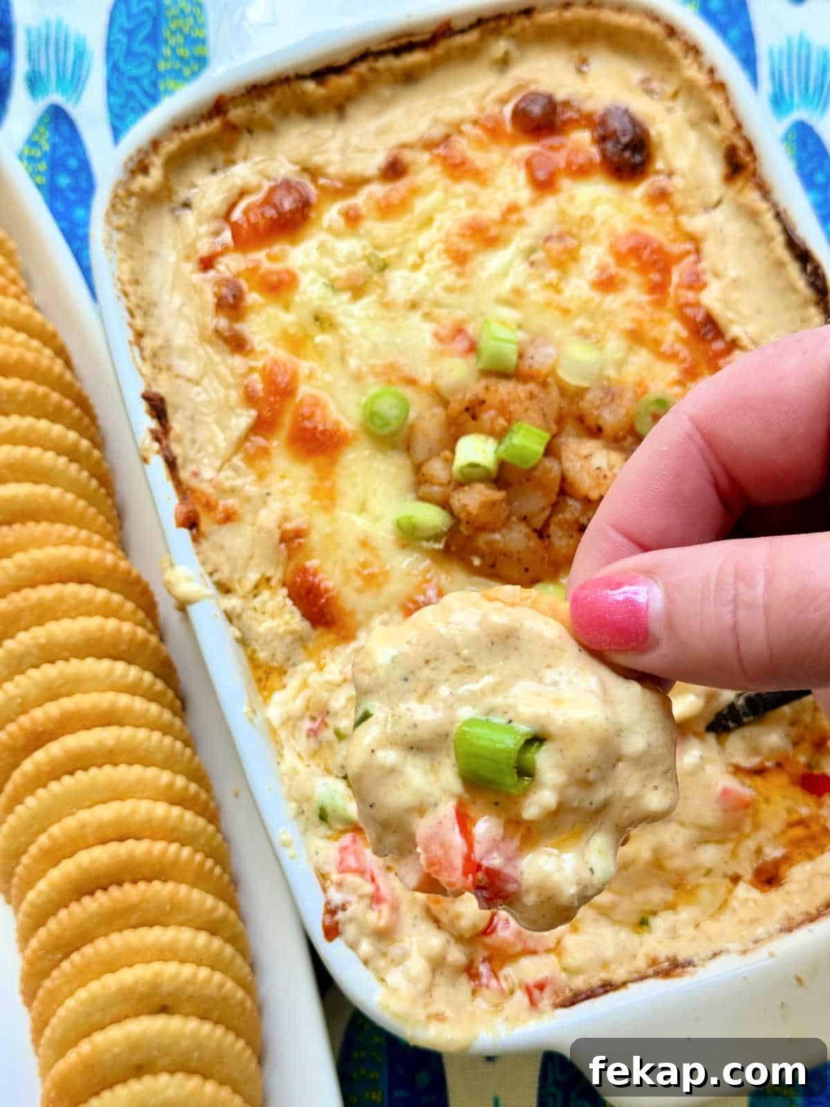 Cajun Shrimp Dip Recipe: Creamy Party Appetizer 5 dipping a cracker into freshly baked cajun shrimp dip