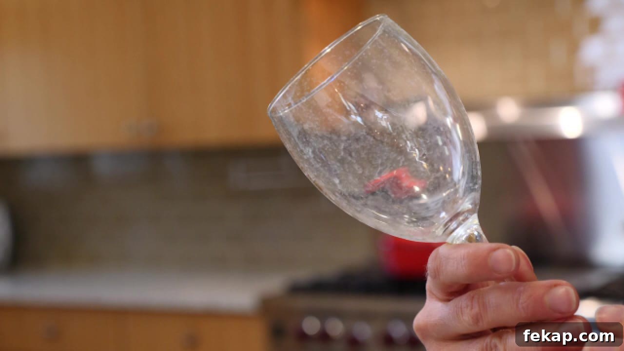 A hand holding a glass with hard water deposits - Using Castile soap to test for hard water. Test for Hard Water