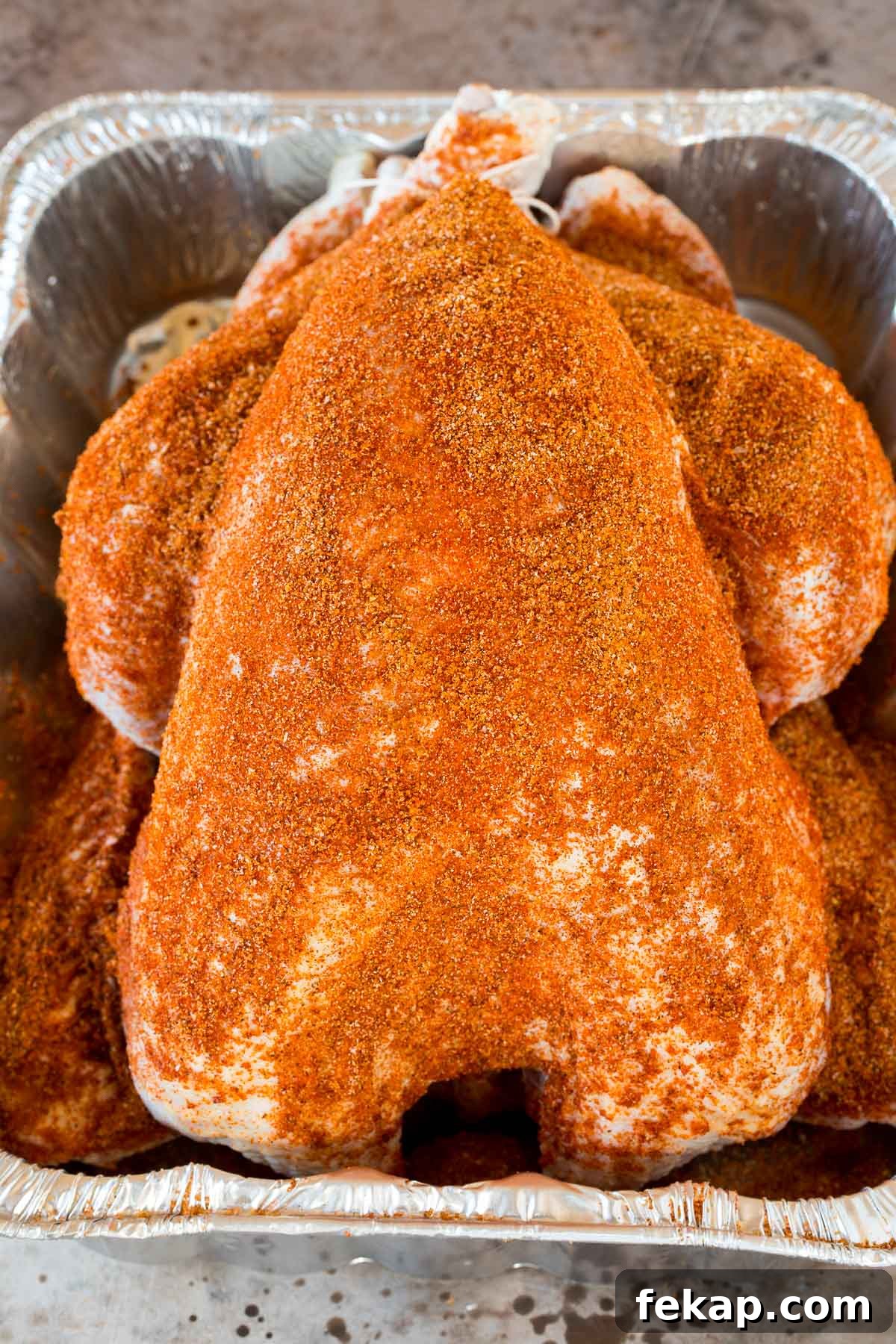 Smoked Turkey Rub Recipe for Juicy Flavorful Turkey 5 A raw turkey coated in seasoning in a pan.