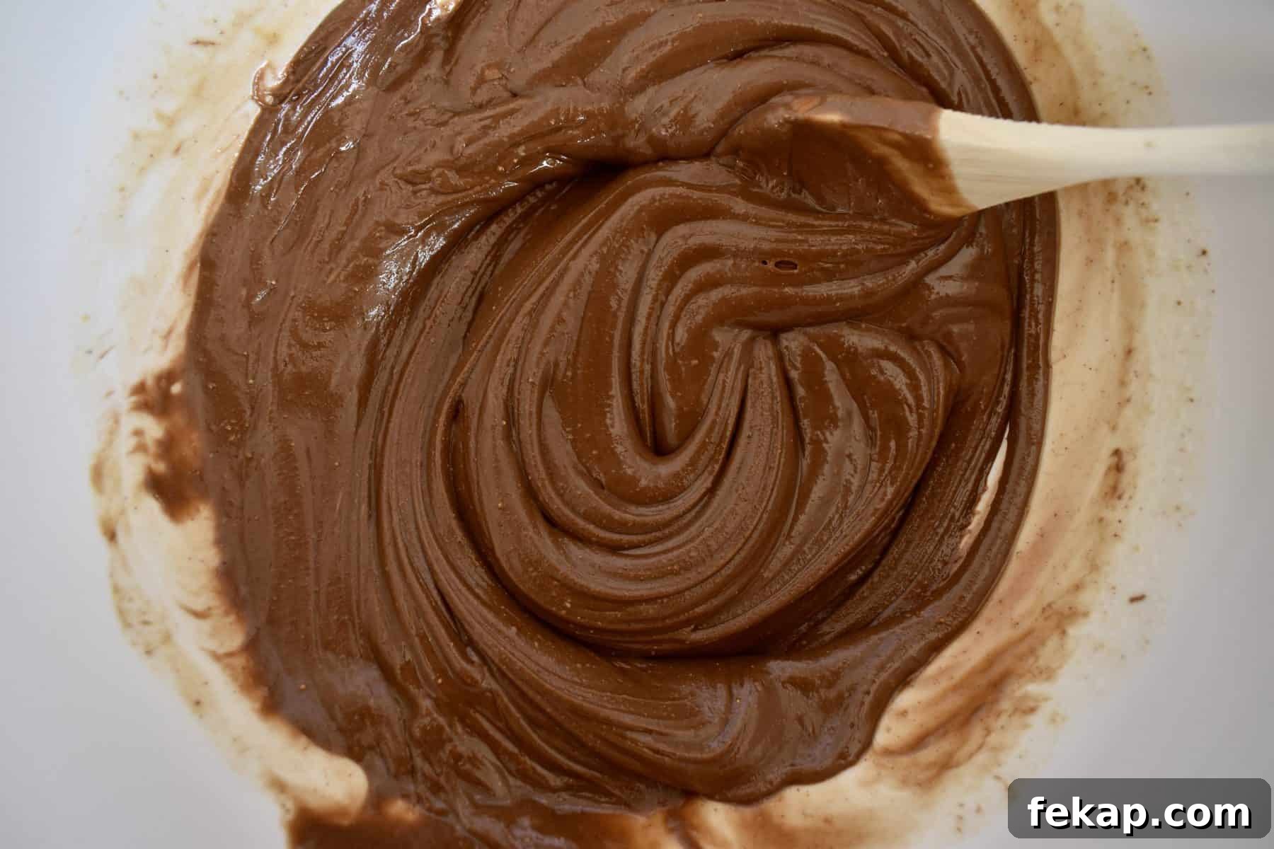 Nutella, peanut butter, and melted butter stirred together in a large white bowl.