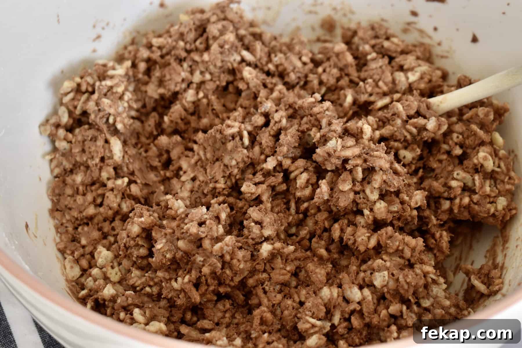 Nutella, peanut butter, Rice Krispies, and powdered sugar combined together in a large white mixing bowl.