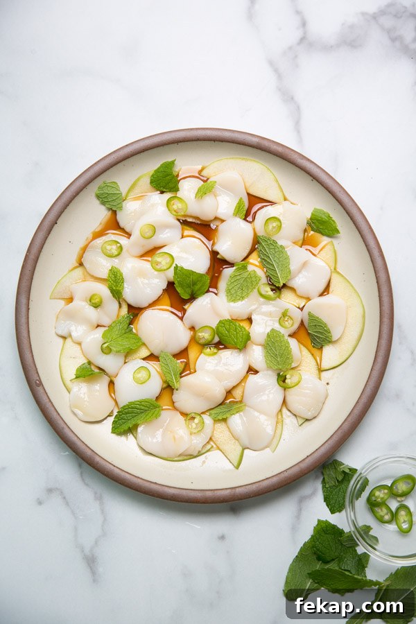 raw scallop crudo on a plate with japanese ponzu sauce mint and peppers