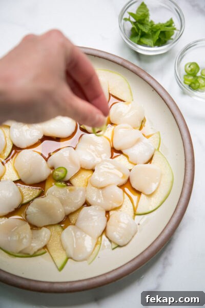 hand garnishing raw scallop crudo 