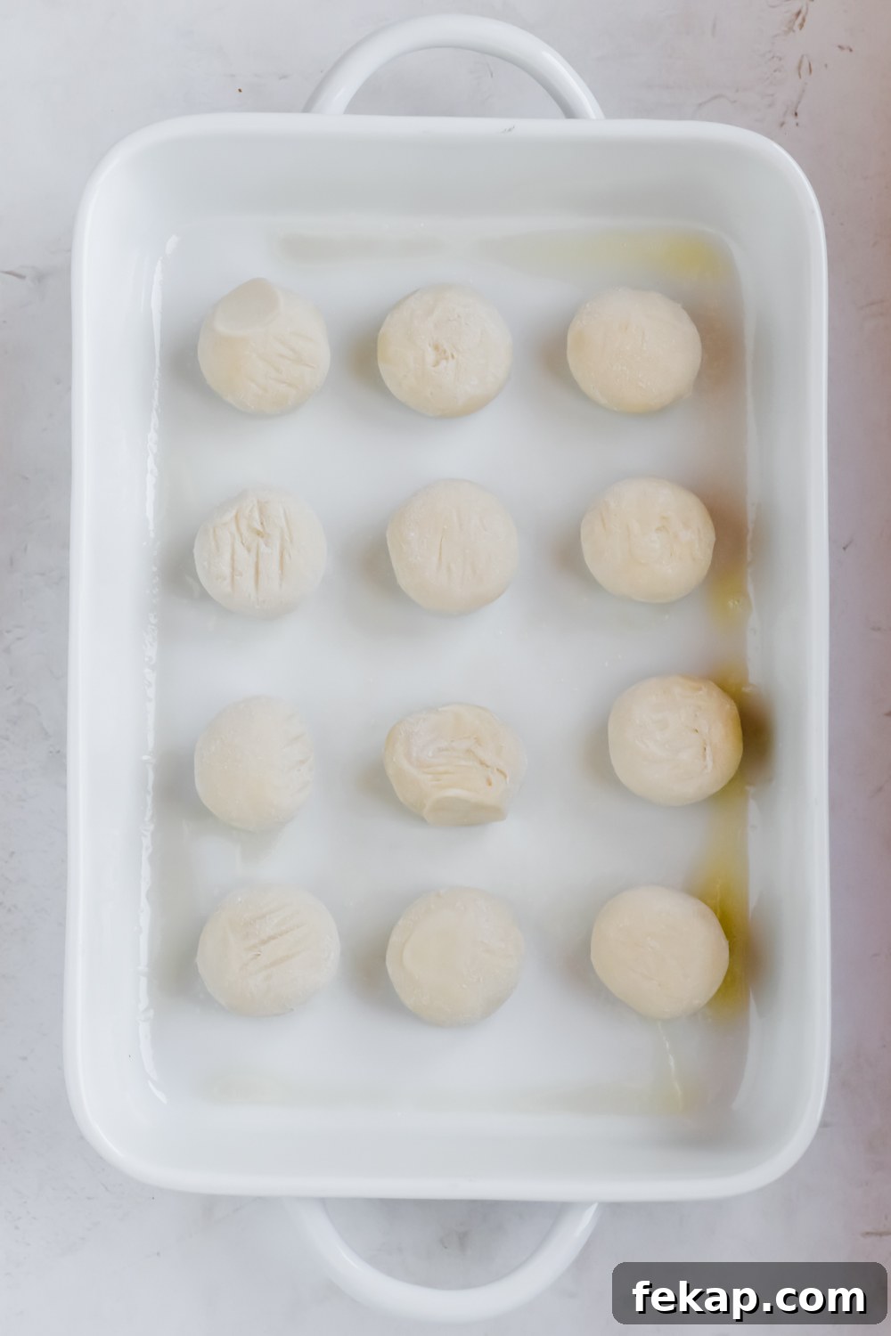 Classic Sticky Buns with Caramel Glaze 4 12 dough balls for old fashioned sticky buns in rows in white baking pan.