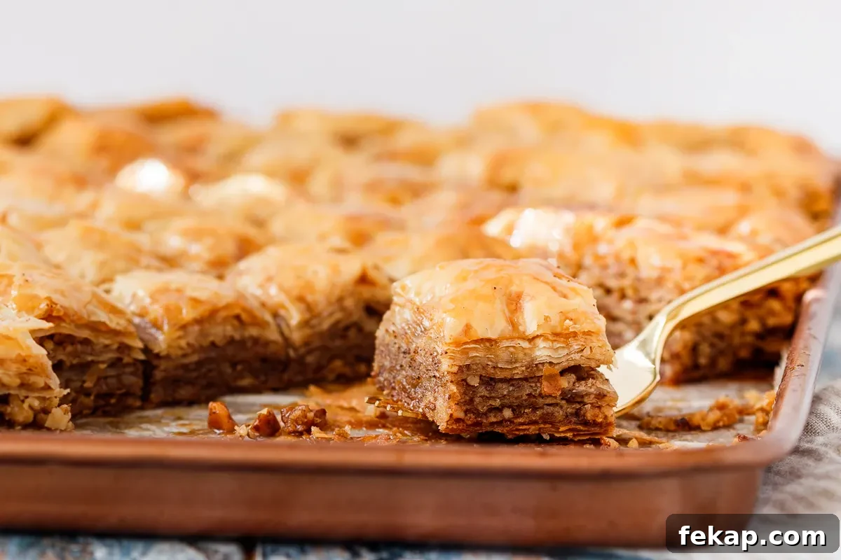 Family Baklava Recipe with Flaky Phyllo and Nuts 6 side view of baklava on a fork showing flaky layers