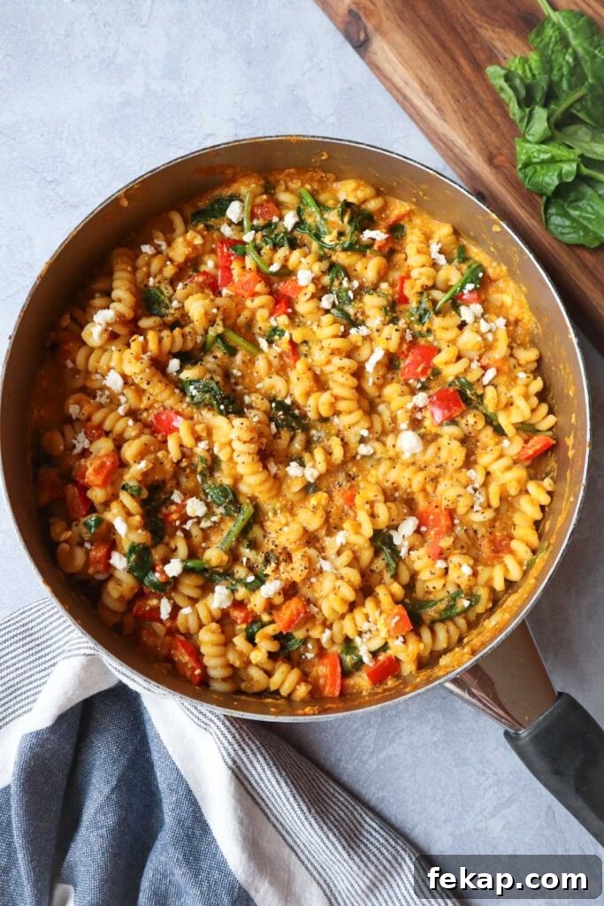 skillet with pumpkin feta pasta topped with feta cheese, red bell pepper, and spinach