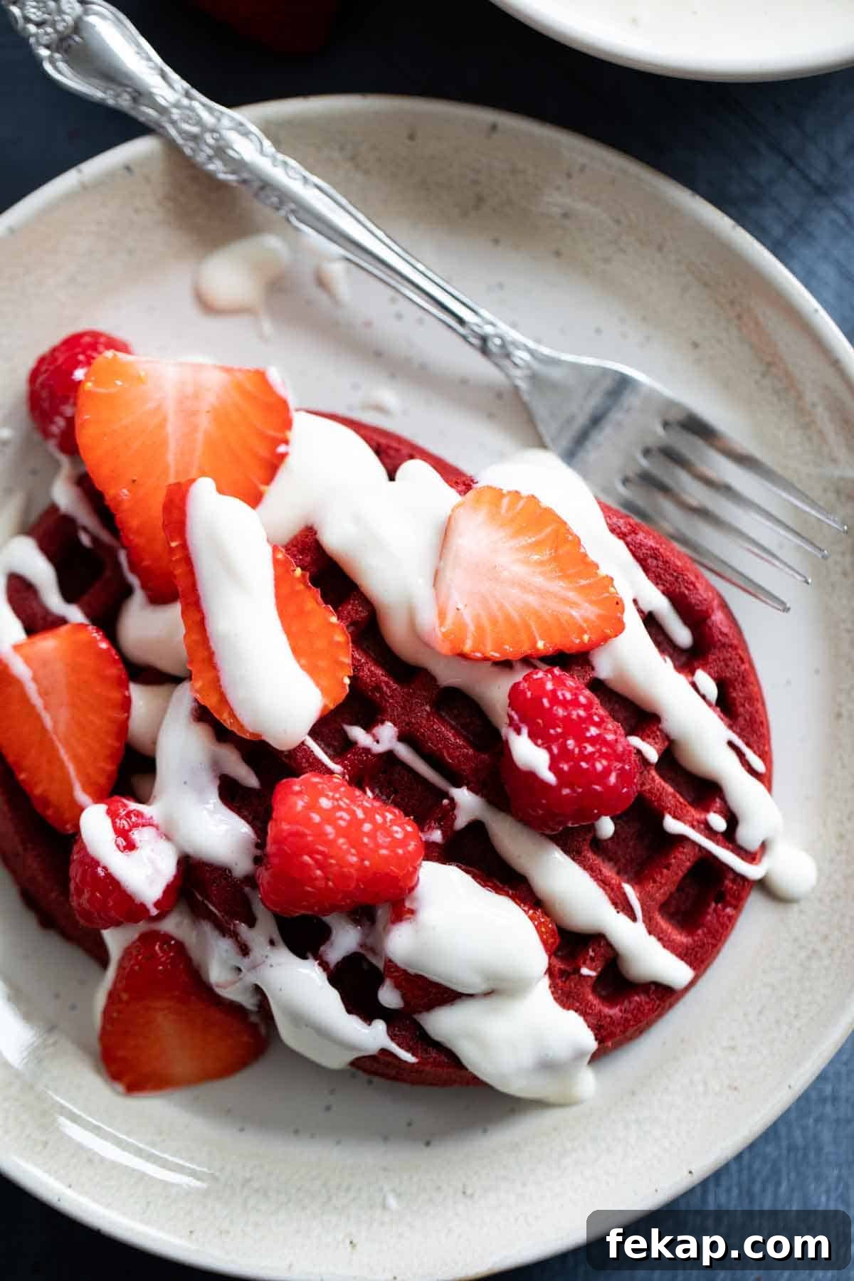 Red Velvet Waffles with berries and cream cheese drizzle Red velvet waffles topped with berries and a cream cheese drizzle.