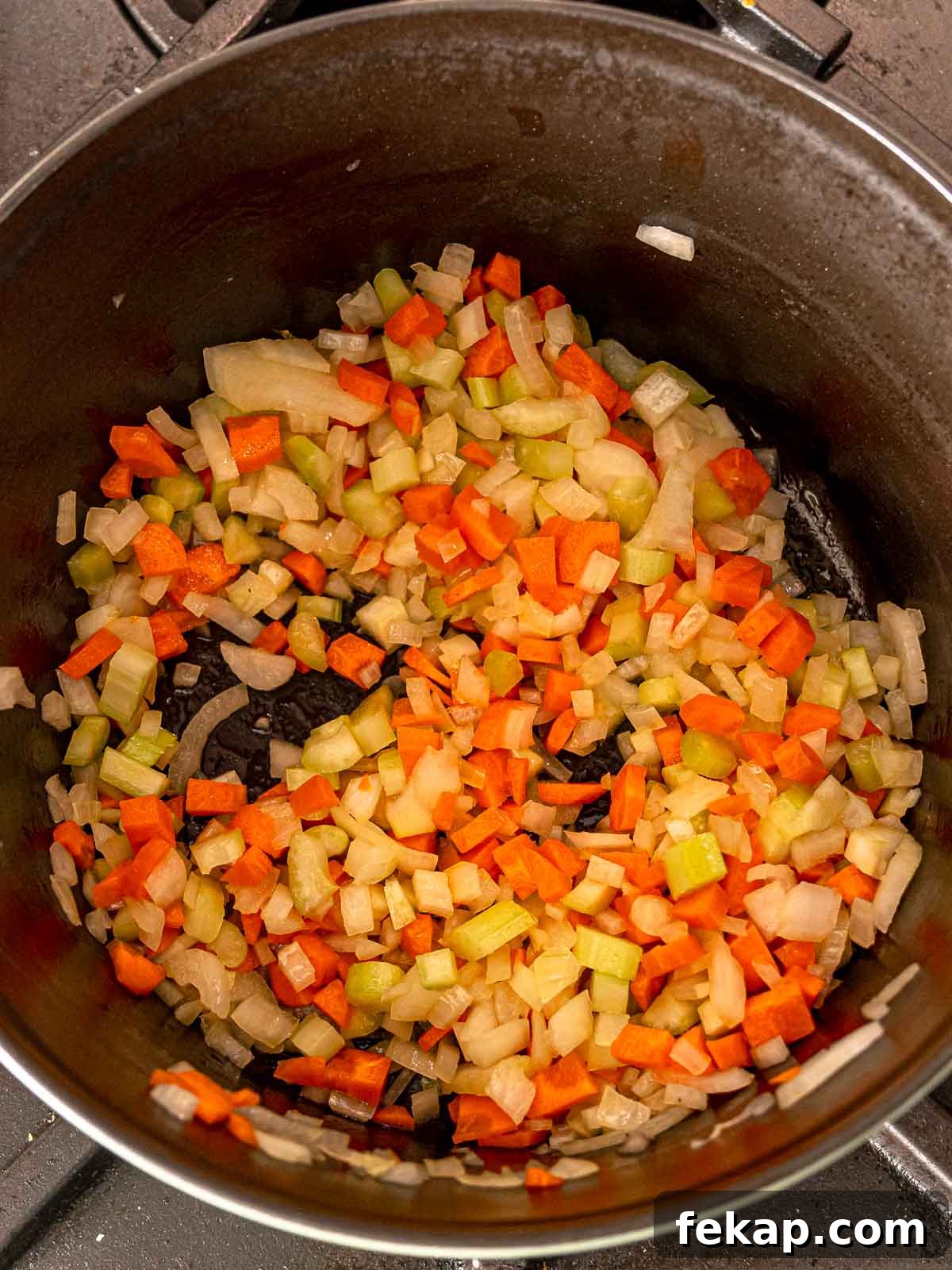 Pot filled with sautéed diced carrots, celery, and onions.