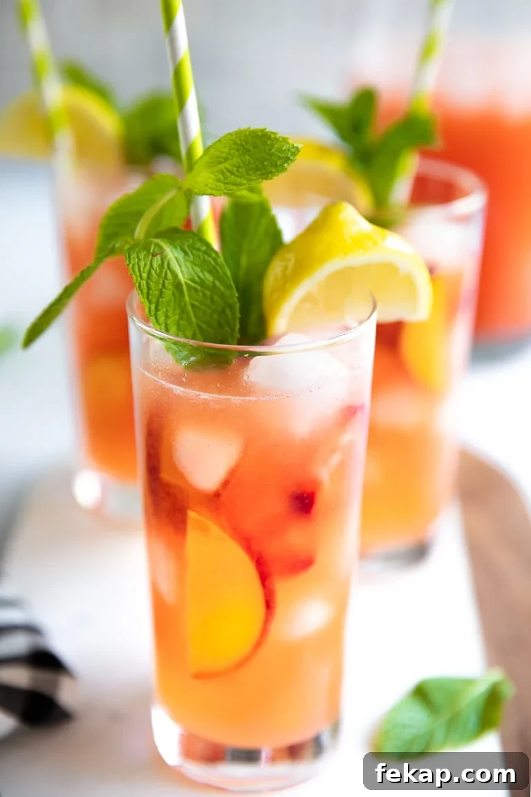 Refreshing Peach Strawberry Lemonade Recipe for Summer 3 Three tall glasses filled with homemade peach and strawberry lemonade with mint.