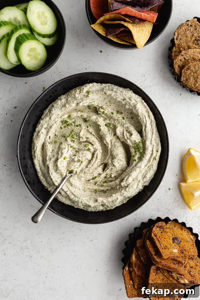 Creamy Vegan Herb Dip Recipe 2 Overhead view of creamy herb dip in a black bowl with a knife inserted into it.