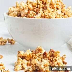 A white bowl filled with caramel popcorn and more popcorn in front of the bowl.