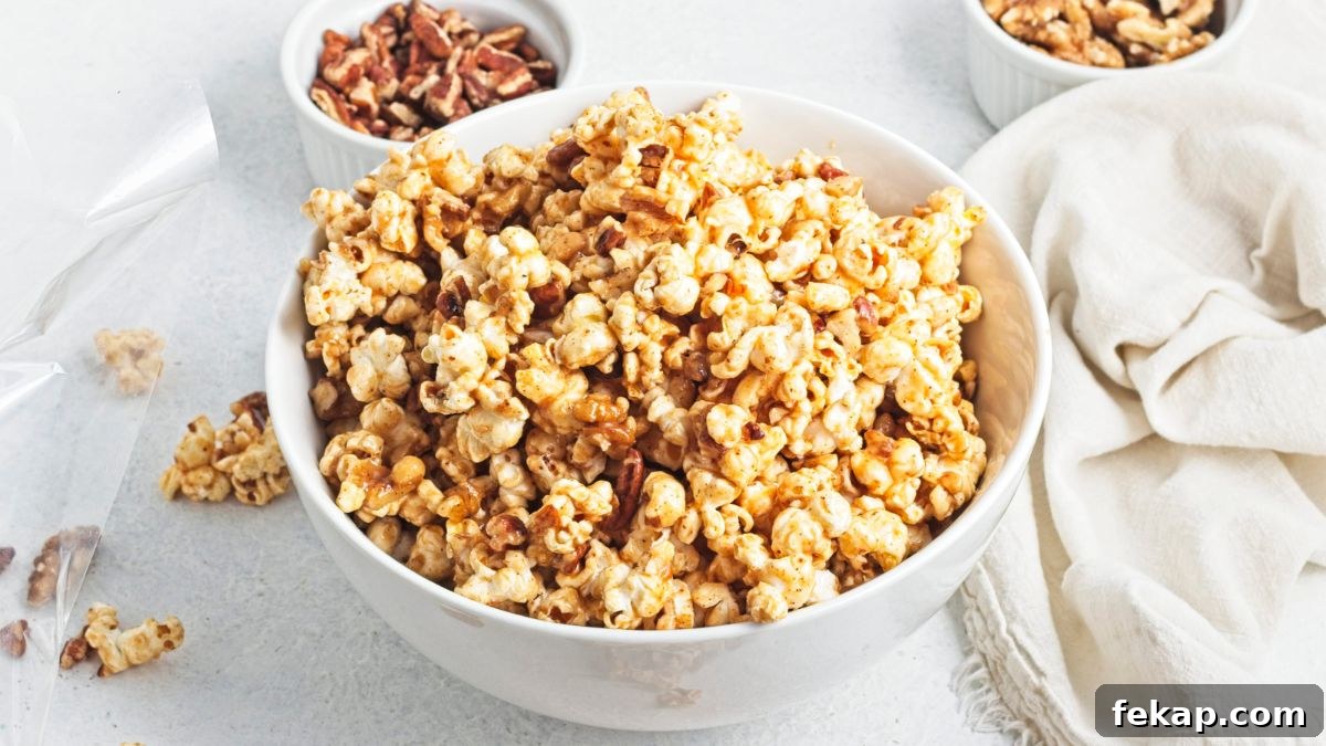A white bowl filled with caramel popcorn and more popcorn around the bowl with chopped pecans behind it.