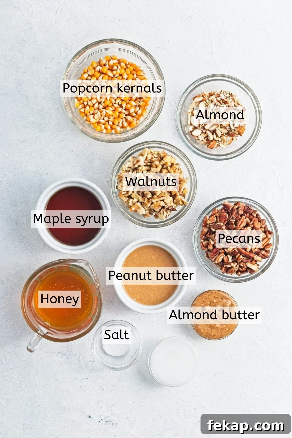 Multiple ingredients like nut butters, raw nuts, maple syrup, and honey in dishes with text labels over top.