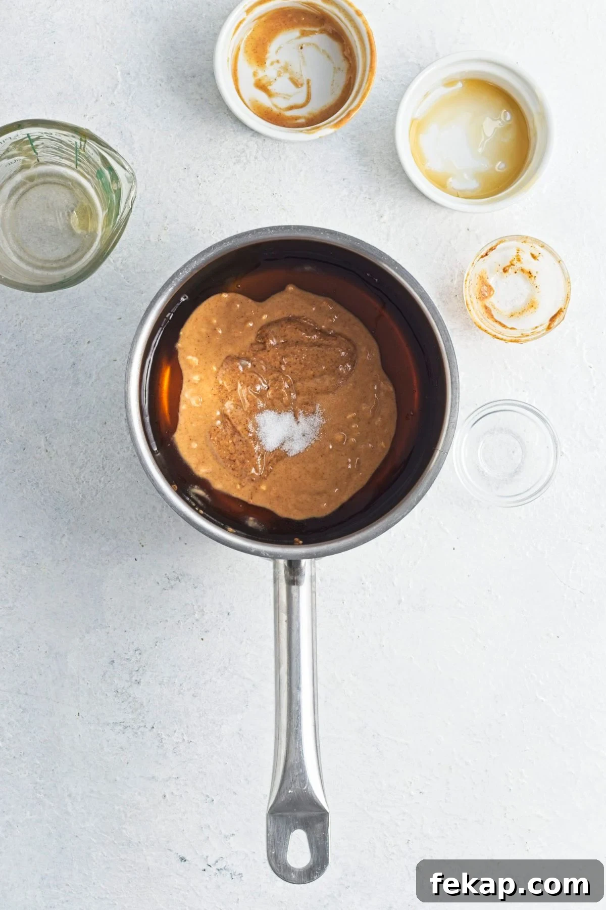Small pot with nut butter, maple syrup, and salt in it and empty bowls around it.