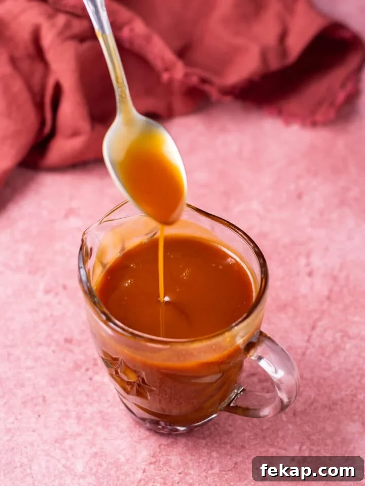 Homemade Salted Caramel Syrup Recipe for Coffee and Desserts 2 Spoon drizzling salted caramel into a small pitcher of caramel syrup