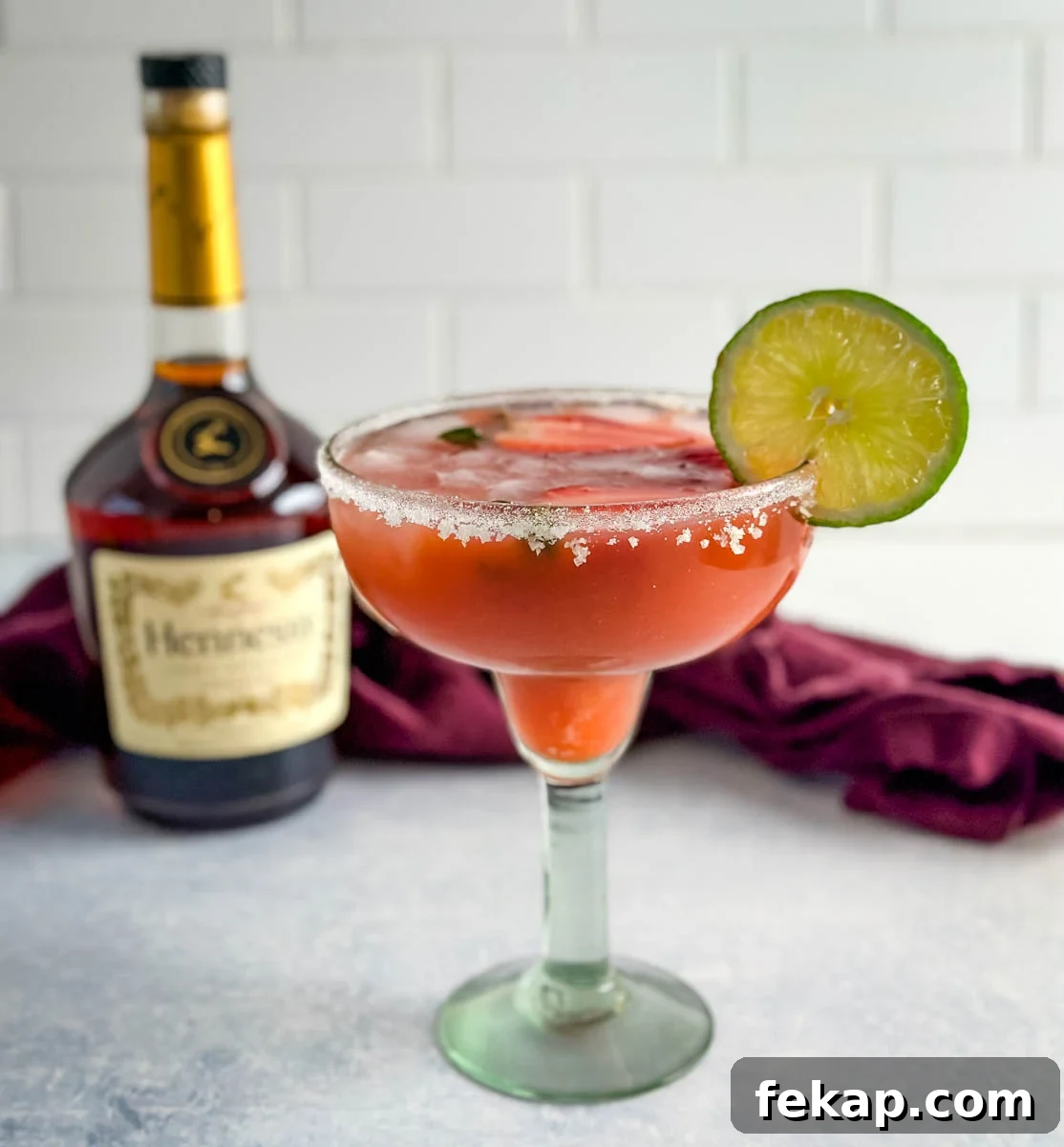 How to Make a Hennessy Margarita Cocktail 2 Hennessy margarita in a glass with strawberries and lime