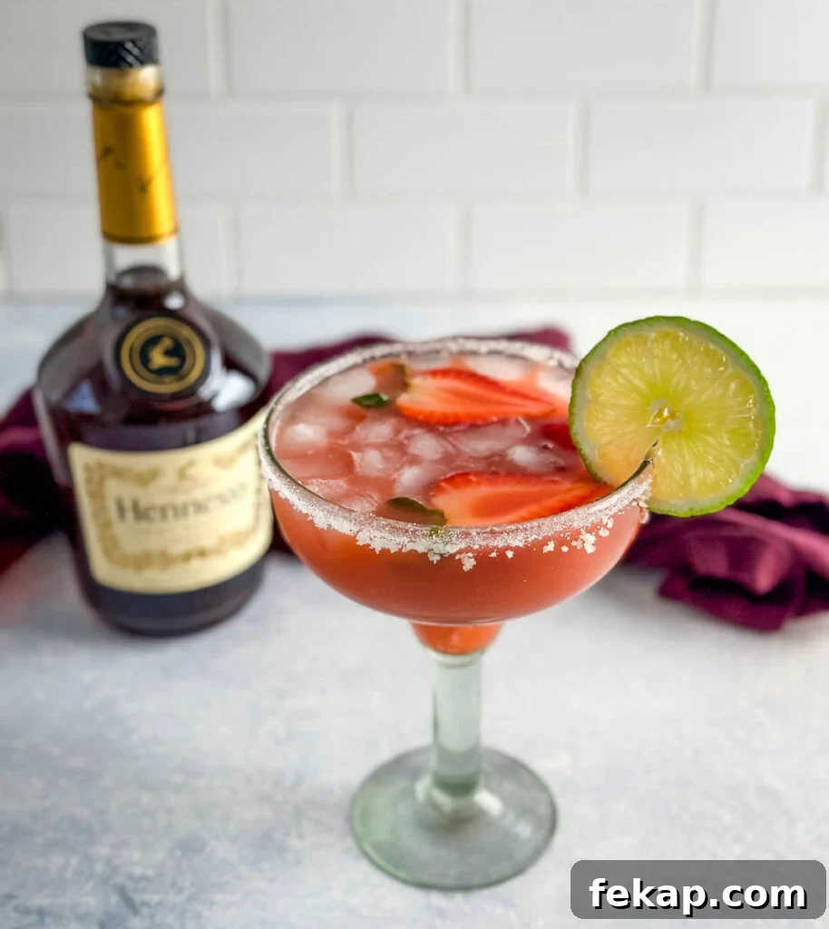 How to Make a Hennessy Margarita Cocktail 11 Hennessy margarita in a glass with strawberries and lime