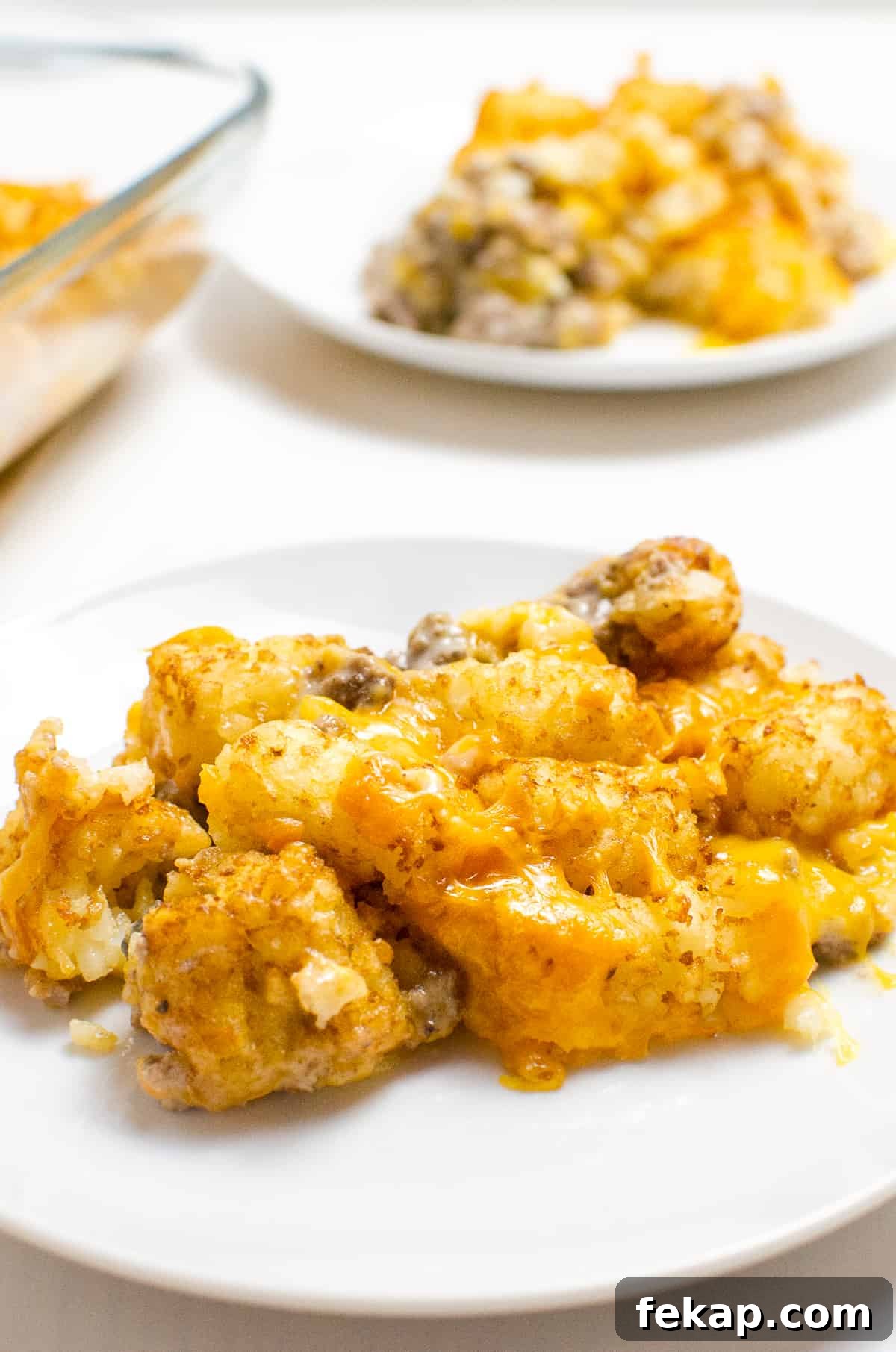 Beef Tater Tot Casserole on white place with another plate and serving in background