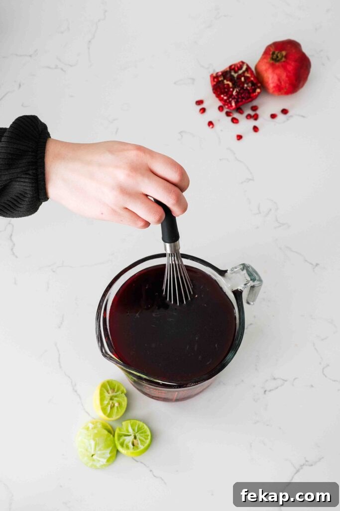 Homemade Pomegranate Sorbet Recipe 7 A whisk stirs pomegranate sorbet mix in a measuring cup.